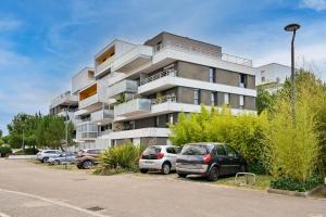 a building with cars parked in a parking lot at Le Rev - à 900m de la plage in La Baule +5 photos