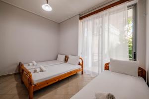 two beds in a room with a window at Panorama Apartment - free rooftop pool entry in Sarandë +16 photos