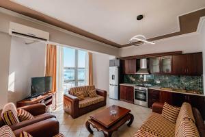 a living room with couches and a tv and a kitchen at Panorama Apartment - free rooftop pool entry in Sarandë