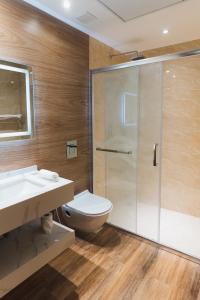 a bathroom with a shower and a toilet and a sink at Milestone Suites by Robinson Properties in Trivandrum +3 photos