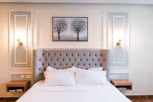 a bedroom with a large bed with white pillows at Milestone Suites by Robinson Properties in Trivandrum