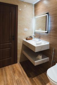 a bathroom with a sink and a mirror and a toilet at Milestone Suites by Robinson Properties in Trivandrum