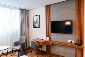 a hotel room with a desk and a television on a wall at Milestone Suites by Robinson Properties in Trivandrum