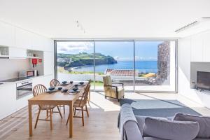 a living room with a table and a large window at Casa Mare in Lagoa +7 photos
