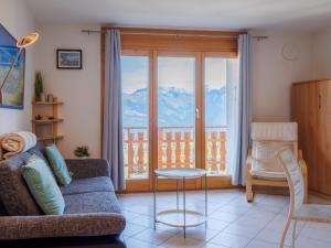 a living room with a couch and a balcony with mountains at Apartment Grand Panorama A11 by Interhome in Nendaz