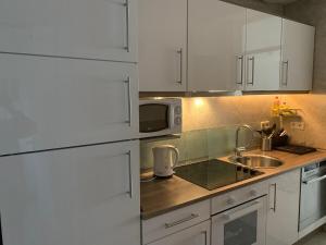 a kitchen with white cabinets and a sink and a microwave at Urlaub im Schwarzwald in Enzklösterle