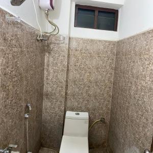 a small bathroom with a toilet and a window at Fortune Heights in Hyderabad