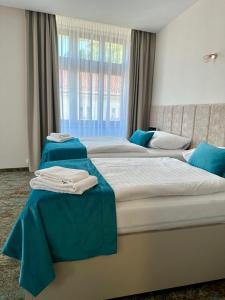 two beds in a hotel room with blue sheets at Hotel Kultúra in Ružomberok