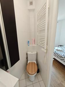 La salle de bains est pourvue de toilettes et d'un siège en bois. dans l'établissement Paris Cozy Studio - 15 Min Paris, à Aulnay-sous-Bois