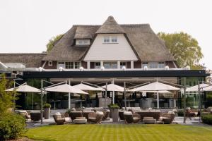 een groot gebouw met stoelen, tafels en parasols bij Pillows Luxury Boutique Hotel Inter Scaldes in Kruiningen