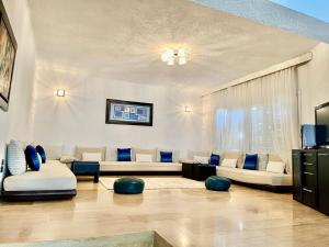 un soggiorno con mobili bianchi e cuscini blu di Dream Villa - Sea View, 4BR, Terrace & Garden a Fnidek Altre 21 foto