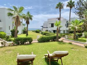 una casa con palme e sedie sull'erba di Dream Villa - Sea View, 4BR, Terrace & Garden a Fnidek