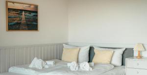 a bed with white pillows and a picture on the wall at Strandkoje - Landhaus in Neustadt in Holstein