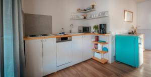 a kitchen with white cabinets and a blue refrigerator at Strandkoje - Landhaus in Neustadt in Holstein