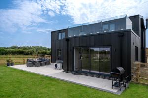 a black modern house with a patio and grass at Blackhills Barn - Crosby in Northallerton