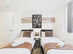 two beds in a room with white walls at Stylish 2 Bedroom Flat | Sleeps 4 | in Brent Station