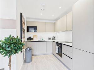 a kitchen with white cabinets and a potted plant at Stylish 2 Bedroom Flat | Sleeps 4 | in Brent Station +4 photos