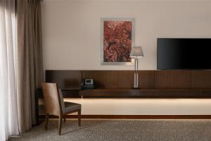 a hotel room with a television and a chair at Dusit Thani LakeView Cairo in Cairo