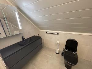 a bathroom with a black toilet and a sink at Havnnes Handelssted in Hamnnes +76 photos