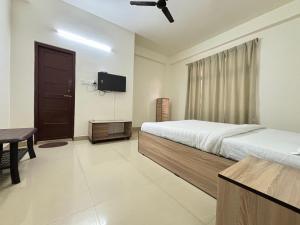 a bedroom with a bed and a flat screen tv at Autumn Inn in Guwahati