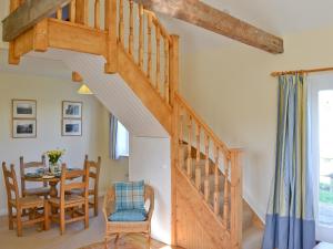 - un escalier en bois dans le salon avec une table et des chaises dans l'établissement Blenheim Cottage-19652, à Peasmarsh