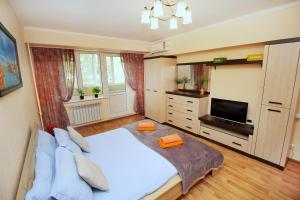 a bedroom with a large bed and a flat screen tv at Меркур возле Аэропорта in Almaty