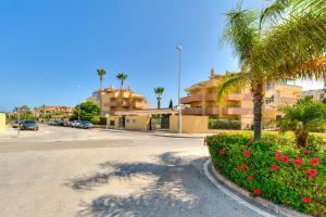 eine Straße mit einem Parkplatz mit Palmen und Blumen in der Unterkunft Penthouse La Noria in Mijas Costa