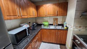 a kitchen with wooden cabinets and a sink and a microwave at sea view luxurious holiday homes in Ajman  +23 photos