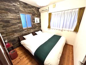 a bedroom with a white bed with a green blanket at 88kawaramachi 一軒家 in Takamatsu