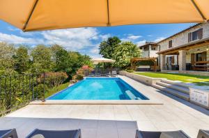 a swimming pool in a backyard with an umbrella at Casa Serena in Bašići