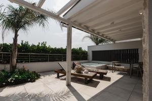 acovered patio with a table and a bench at Hotel Golden Sun in Néa Meságkala +14 photos