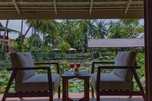 two chairs and a table with two glasses of wine at Villa Oasis in Luang Prabang