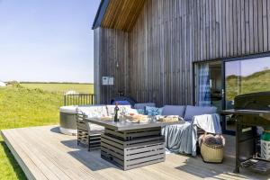 a patio with a couch and a table and a grill at No 9 The Vista, Willingcott, Woolacombe in Woolacombe