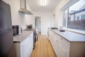 a kitchen with white cabinets and a large window at Victoria Retreat in Workington