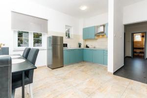 a kitchen with blue cabinets and a table and chairs at Villa Sky with pool in Vrh