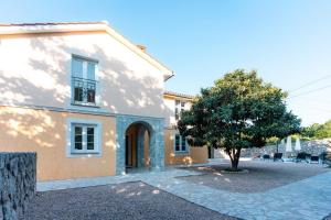 a house with a tree in front of it at Villa Sky with pool in Vrh