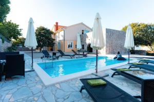 a villa with a swimming pool with umbrellas at Villa Sky with pool in Vrh