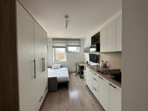 a kitchen with white cabinets and a bed in a room at Starter III in Wrocław