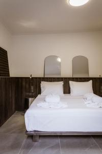 un dormitorio con una cama con sábanas y almohadas blancas en HUGme Suite, en Kalithies