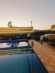 two people standing next to a swimming pool at Hari Kamal Gust House , Farms & Swimming Pool in Dhānd