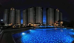 a large swimming pool with blue lights in front of buildings at RCL Cebu Condo property in Mactan Island