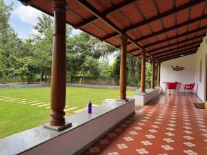 にあるPhalguni Farm Stayの屋根付きの家のポーチ(テーブルと椅子付)