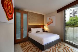 a bedroom with a bed and a large window at Hotel Angeleno in Los Angeles