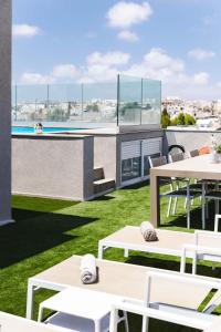 a patio with white tables and chairs and a pool at Villa Ixoria Unit 2 with Rooftop Pool by ArcoBnb in St Julian's