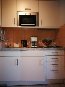 a kitchen with white cabinets and a microwave at Apartement "Am Südstrand" in Burgtiefe auf Fehmarn  +11 photos
