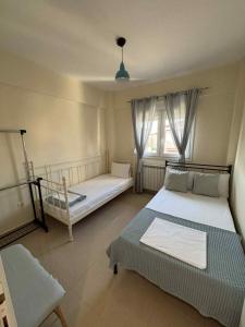 une chambre avec deux lits et une fenêtre dans l'établissement Villa Dina, à Paralia Dionisiou