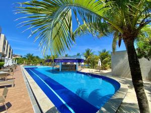 a swimming pool with a palm tree next to it at Lindo Flat Garden beira-lago e perto da praia in Camaçari