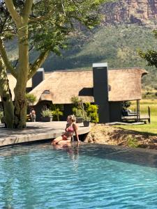 a woman sitting in a swimming pool at Honeyguide Conservation Lodge in Golders Green