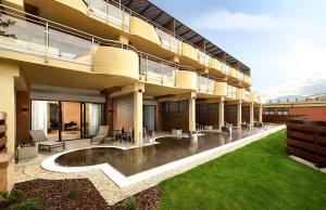 an apartment building with a large patio and grass at Hotel Galeria Thermal Bešeňová in Bešeňová