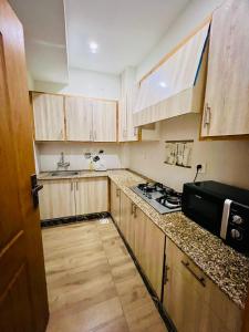 a small kitchen with wooden cabinets and a stove at Modern 2-Bedroom Apartment Only For Families in E-11 Northern strip in Islamabad
